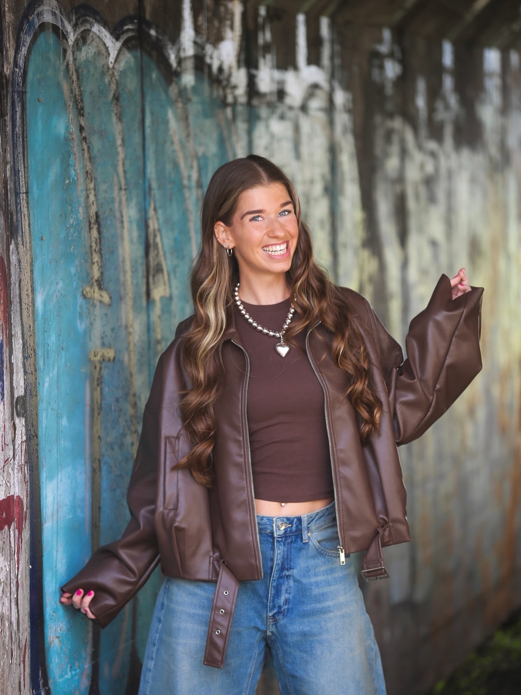 Portret van Ashley in een bruine leren jas voor een blauwgroene houten wand